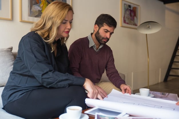 A young couple sitting at a table, reviewing documents with a financial advisor. The advisor is pointing at a graph showing increasing home values.