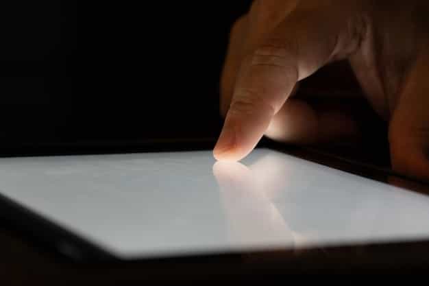 A close-up shot of a hand carefully examining the screen of an open-box tablet for scratches. The lighting is focused on the screen to highlight any imperfections.