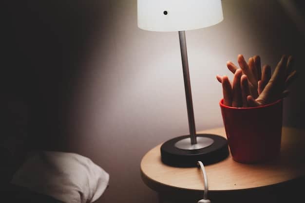 A close-up shot of a smart bulb illuminating a bedside table lamp. The light is soft and warm, creating a cozy and inviting atmosphere. The focus is on the smart bulb itself, highlighting its modern design and energy-efficient features.