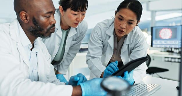 A group of diverse scientists in a modern laboratory setting analyzing data on multiple screens, symbolizing advanced research into disease prevention and treatment.