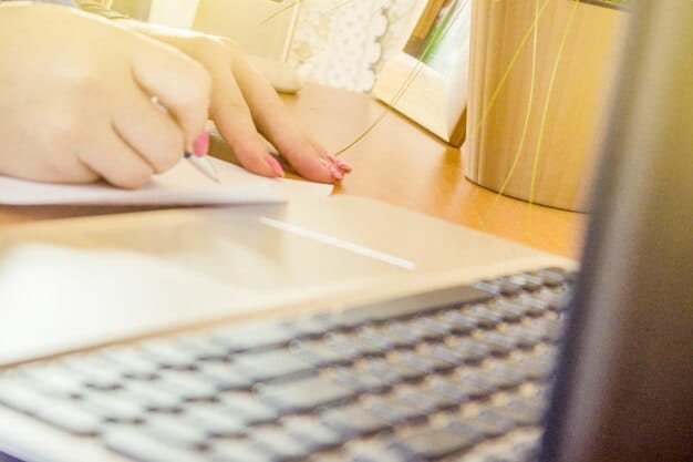 A detailed shot of hands typing on a laptop keyboard, with financial aid application forms and a pen visible on the desk, emphasizing the process of applying for grants and scholarships.