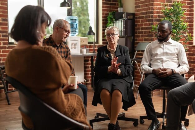A diverse group of older adults actively participating in a financial planning seminar, listening intently to a speaker. The scene suggests engagement and learning about retirement strategies.