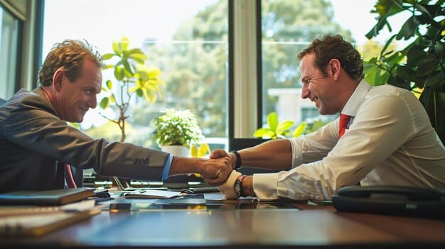Two people shaking hands across a table in an office, symbolizing a successful negotiation or agreement reached.