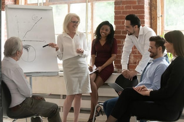 A group of diverse employees participating in a leadership training session. They are actively taking notes, asking questions, and engaging with the instructor. The setting is a modern conference room, emphasizing the importance of continuous learning and development in Leadership Development: Cultivating the Skills to Lead and Inspire Others.