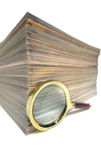 A magnifying glass examining a stack of documents titled 
