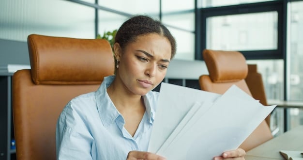Close-up shot of a person reviewing insurance paperwork with a concerned expression. The paperwork is slightly blurred, emphasizing the complexity of insurance. A pen is resting on the document, suggesting careful study.